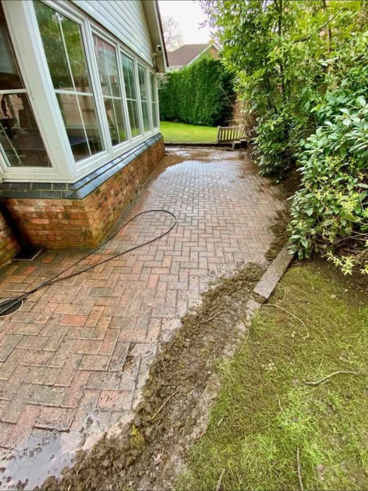 Block paving patio being cleaned alongside a bay window